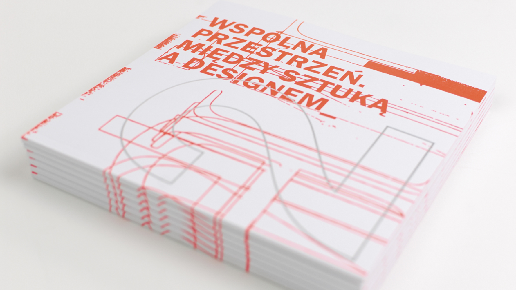 Stos ułożonych równo katalogów. Na białej okładce pomarańczowy nadruk: WSPÓLNA PRZESTRZEŃ. MIĘDZY SZTUKĄ A DESIGNEM_. Obraz dopełnia zamieszczona poniżej w poziomie ogromna  cyfra 2, obwiedziona jasnoszarym konturem. Została nałożona na pomarańczowe kontury liter i cyfr podobnej szerokości.