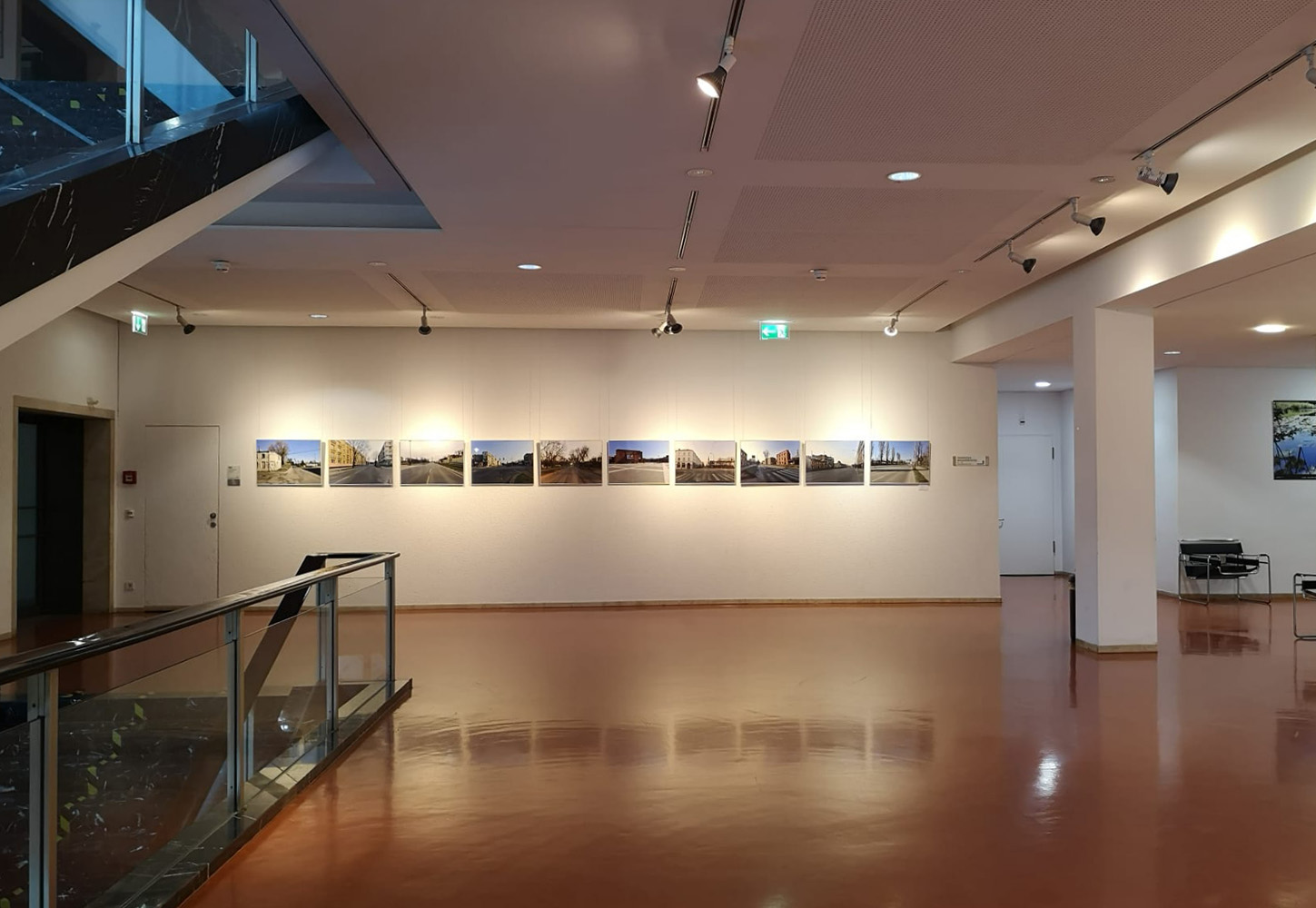 Sala ekspozycyjna o imponującej rozmiarem przestrzeni. Na przeciwległej, białej ścianie rozmieszczono w niedużych odstępach 10 fotografii jednakowej wielkości. Zachowują jedność stylistyczną i tematyczną rozumianą w pierwszym oglądzie, gdyż na każdym z nich można zauważyć architekturę osadzoną w szerszym ujęciu krajobrazu i w perspektywie zbieżnej, chociaż niektóre wykonano w różnym świetle dnia i innej aurze